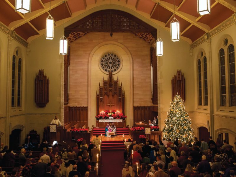 interior of a large church with a bright christmas tree and many people